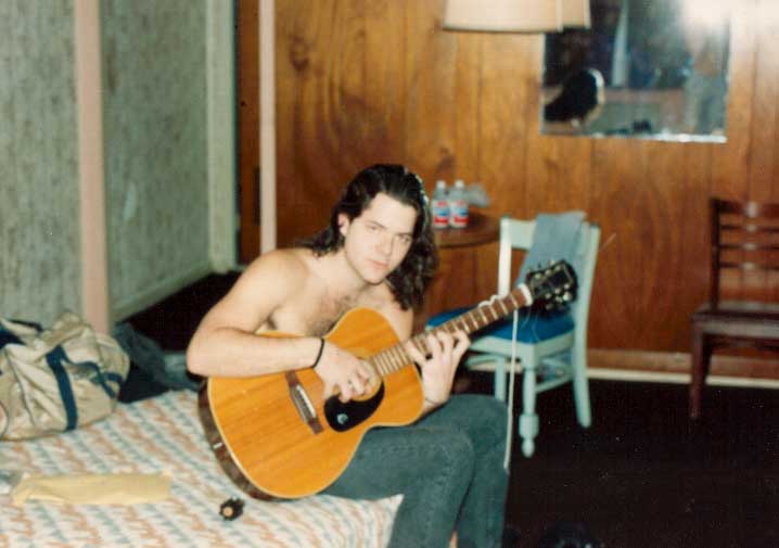 A younger Richard seated with a guitar
